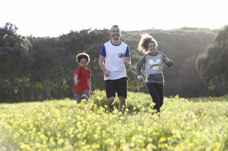 A dada and two children enjoy walking through meadow flowers together (Disney Lets Go)