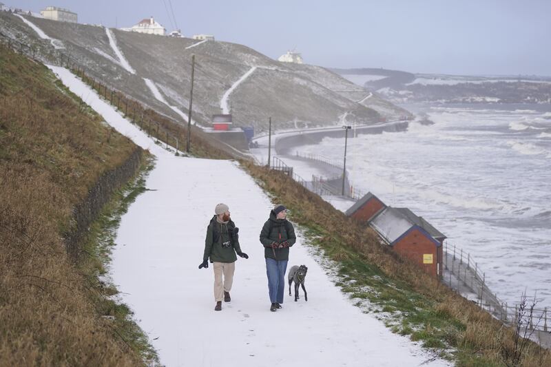 People walk along a snow-covered path in Whitby, North Yorkshire