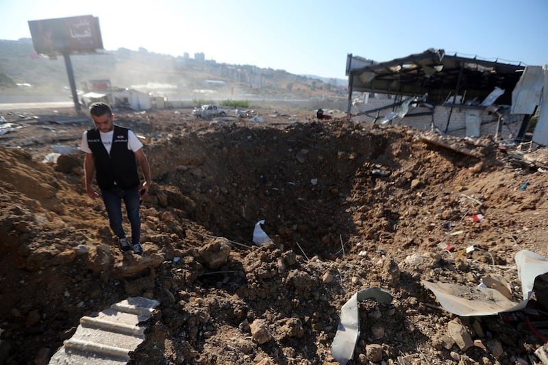 A Lebanese police intelligence officer stands near a crater at the site of an Israeli airstrike that hit a hangar in the southern town of Jiyeh, Lebanon, on Wednesday (Mohammed Zaatari/AP)