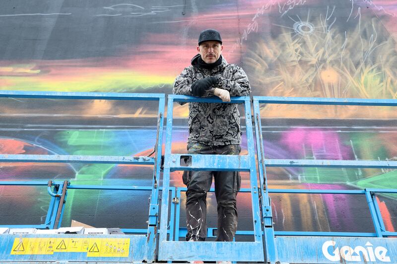 Street artist Dan Kitchener working  on a new mural on 135 Ormeau Road, it depicts the Ormeau Bridge lit up at night and reflected in the Lagan River and was commisioned by the Lower Ormeau Road Traders' Association after they received funding to make the road a more viable business destination. PICTURE: MAL MCCANN