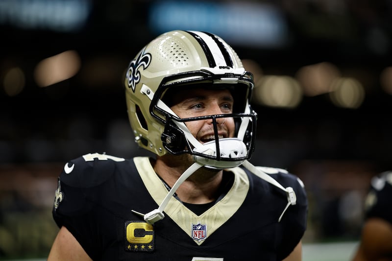 Derek Carr dressed in New Orleans Saints game uniform, with a gold helmet smiling