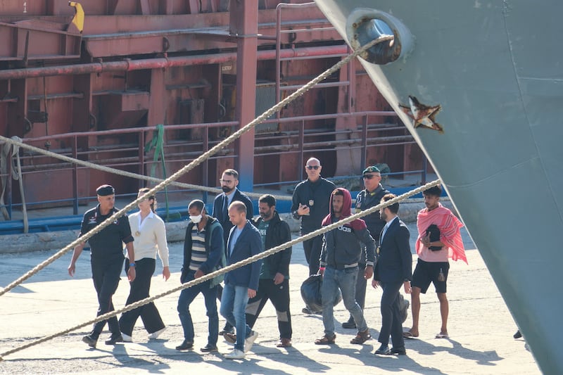 Migrants and security officials walk at the port of Shengjin, northwestern Albania (Vlasov Sulaj/AP)