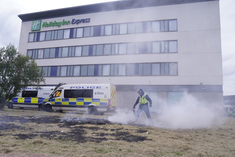 A police officer extinguishes a fire during an anti-immigration demonstration outside the Holiday Inn Express in Rotherham