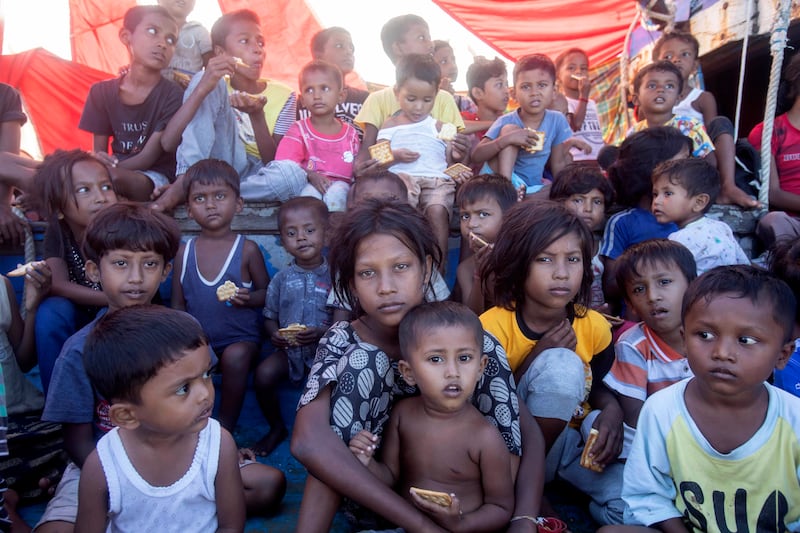 Rohingya refugee children sit on the deck of their boat anchored off the coast of Aceh as locals refuse to permit them to make landfall (Binsar Bakkara/AP)