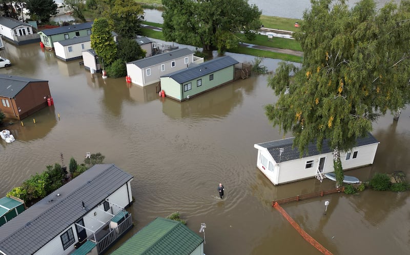 A man wades through floodwater at Cogenhoe Mill holiday park in Northamptonshire, which is next to Billing Aquadrome holiday park