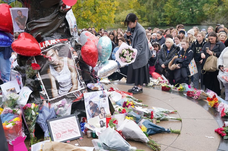 A person laying flowers during a vigil for 31-year-old One Direction singer Liam Payne at Hyde Park in central London