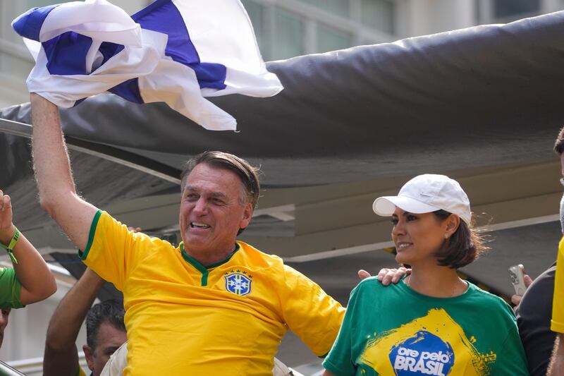 Former President Jair Bolsonaro waves an Israeli flag as he addresses supporters, accompanied by his wife Michelle (Andre Penner/AP)