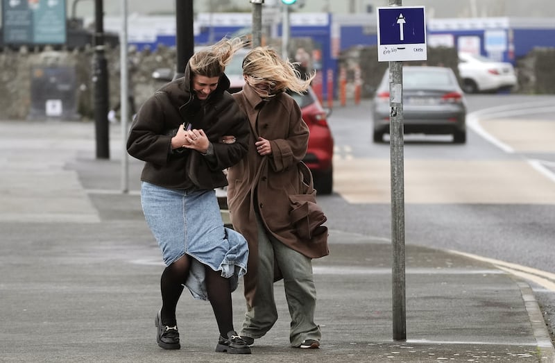 Two young women struggling to walk on the promenade in Salthill, Galway during Storm Ashley