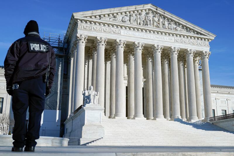 A police officer patrols outside the US Supreme Court on Friday. The court will decide whether Donald Trump can be kept off the 2024 presidential ballot (Mariam Zuhaib/AP)