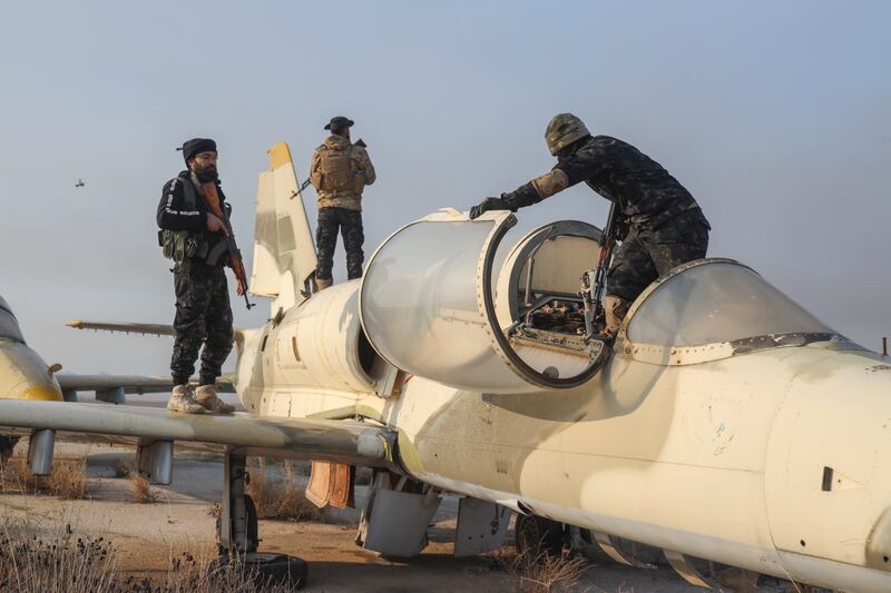 Syrian opposition fighters stand on an aircraft at the Al-Nayrab military airport after taking control of the facility on the outskirts of Aleppo (Omar Albam/AP)