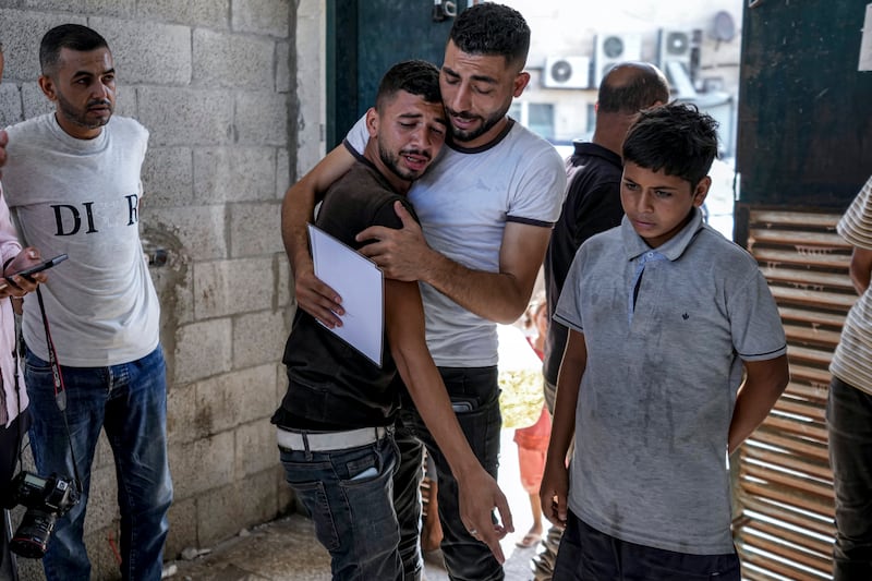 Palestinians mourn their four-day-old twin relatives, killed in the Israeli bombardment of the Gaza Strip, as he holds their birth certificates, at a hospital morgue (Abdel Kareem Hana/AP)