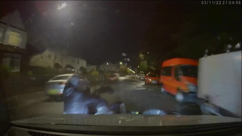 A video screen grab shows the moment a marked police car knocks the rider and pillion passenger off an electric motorbike