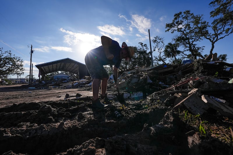 A maintenance manager tries to find a water shutoff valve amid the rubble in Horseshoe Beach, Florida (AP Photo/Gerald Herbert)