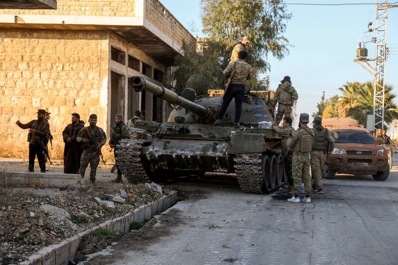 Opposition fighters stand on top of a captured Syrian army armoured vehicle in the town of Maarat al-Numan, south-west of Aleppo (Omar Albam/AP)