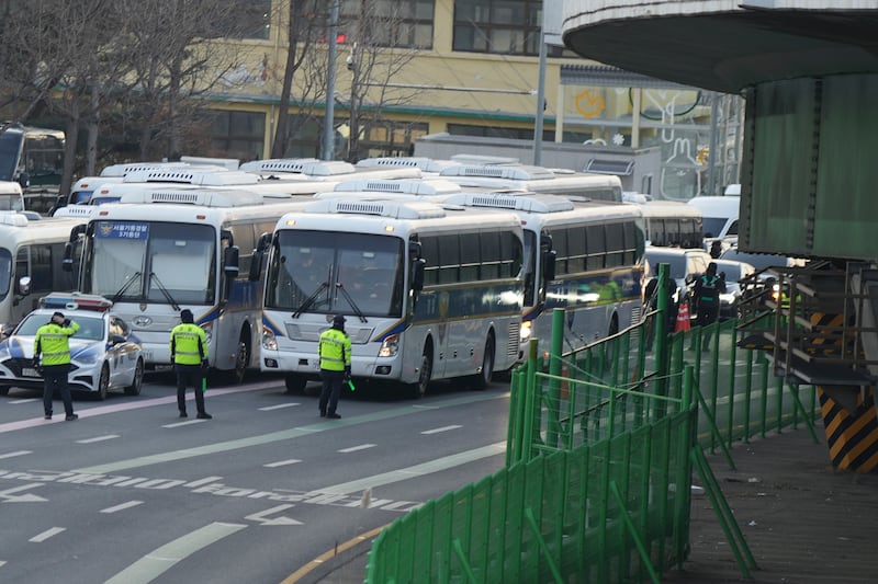 Vehicles, right, carrying investigators from the Corruption Investigation Office for High-ranking Officials arrive at the gate of the presidential residence (Lee Jin-man/AP)