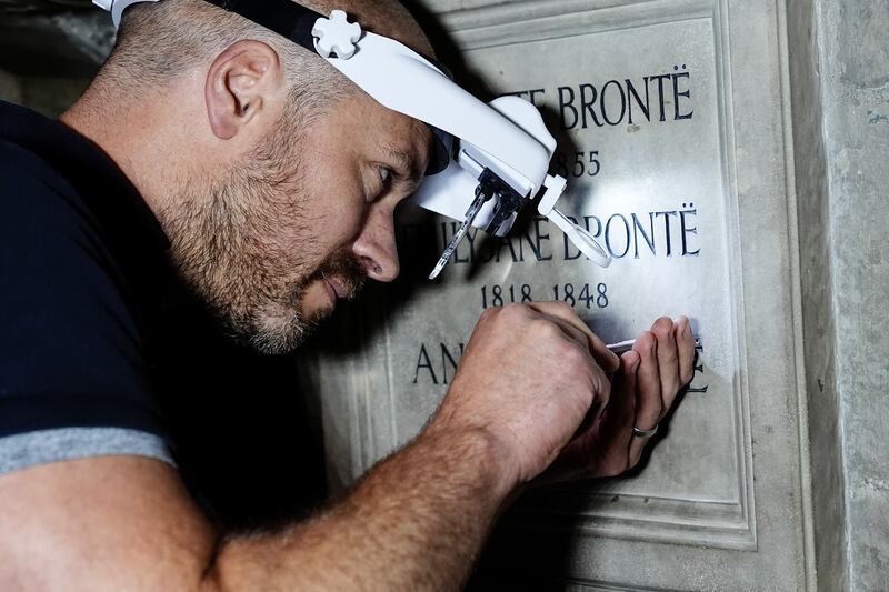 Stonemason Mark Croll adds the finishing touches to the memorial to Charlotte, Emily and Anne Bronte at Poets’ Corner in Westminster Abbey, London