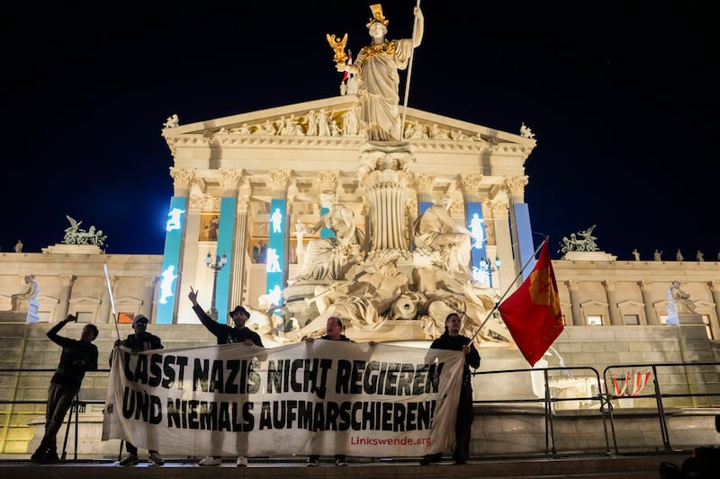 Anti-right-wing protesters shout slogans and hold a banner that reads “Don’t let Nazis rule and never let them march” in front of the parliament building in Vienna (Andreea Alexandru/AP)