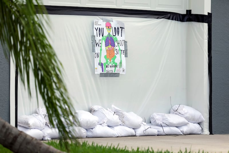 A sign warns looters on a garage door taped with plastic and sand bags (Mike Carlson/AP)