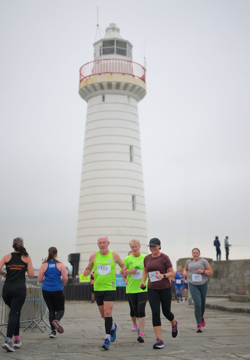 Group of runners in 5k race in front of white lighthouse