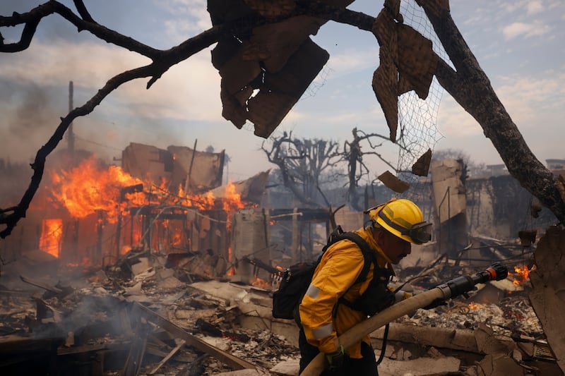 A firefighter battles the Palisades Fire around a burned structure in the Pacific Palisades neighbourhood of Los Angeles (AP/Etienne Laurent)