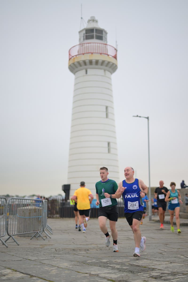 Group of runners in 5k race in front of white lighthouse