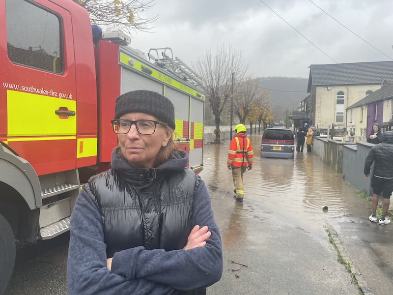 Resident Claire Instrell, whose home appears to have avoided being flooded but experienced it four years ago, watches proceedings on Sion Street, in Pontypridd, Wales