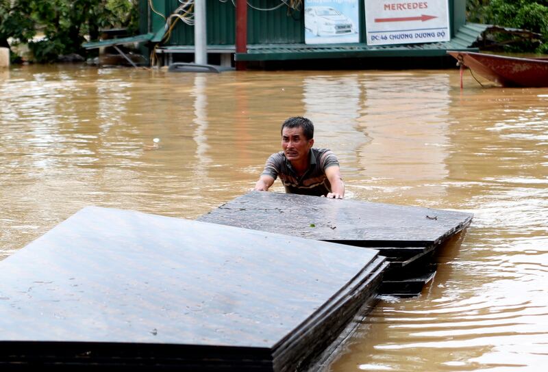 A man pushes a stack of plyboards in floodwater in Hanoi (Huy Han/AP)