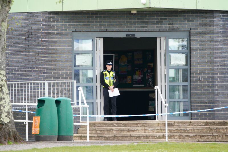 A police officer stands at the entrance to the school in Ammanford, Carmarthenshire, after an arrest was made