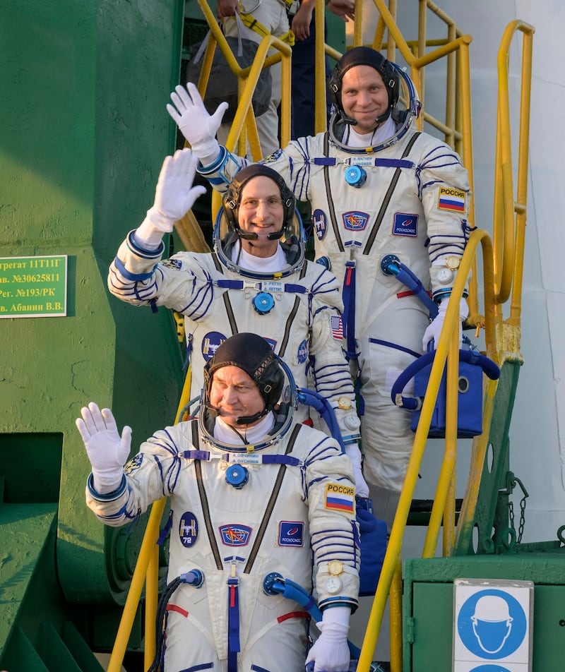 Roscosmos cosmonaut Ivan Vagner, top, Nasa astronaut Don Pettit, centre, and Roscosmos cosmonaut Alexey Ovchinin wave farewell prior to boarding the Soyuz craft (Bill Ingalls/NASA via AP)