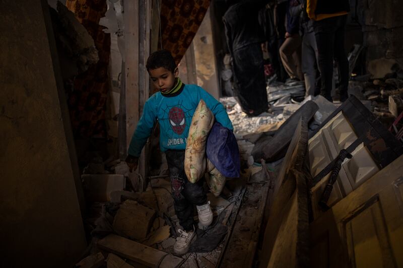 Palestinians collect their belongings from their damaged house after an Israeli airstrike in Rafah, southern Gaza Strip (Fatima Shbair/AP)