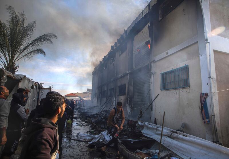 Palestinians try to extinguish a fire at a building of a UNRWA vocational training centre which displaced people use as a shelter (AP Photo/Ramez Habboub)