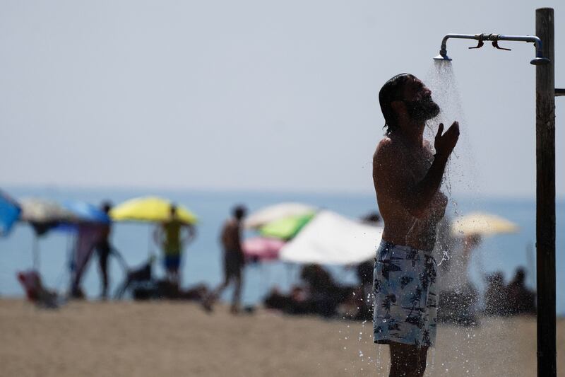 A man takes a shower on a beach on a hot day in Ostia, near Rome (AP)