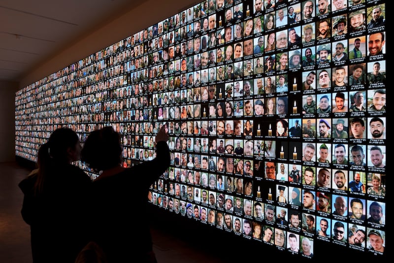 Visitors look at photos of Israeli people who were killed during Hamas’s attack on October 7 and those who have died during the Israel-Hamas war in the Gaza Strip, displayed on a giant screen at the National Library in Jerusalem (Leo Correa/AP)
