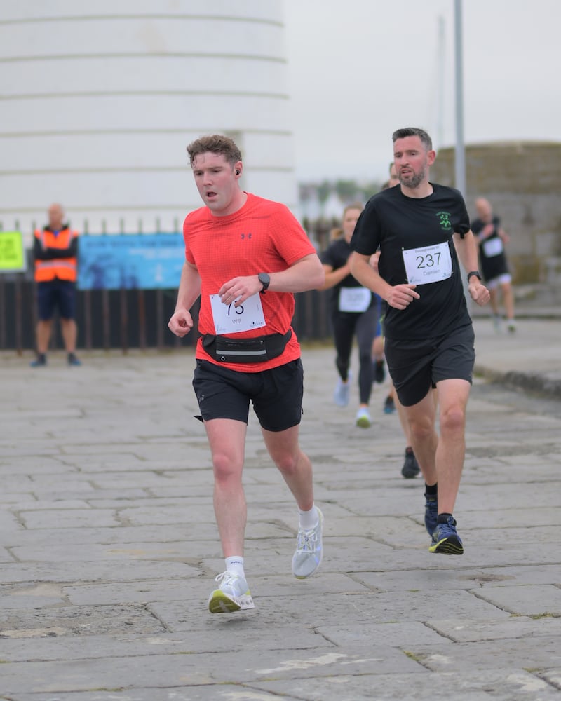 Group of runners in 5k race in front of white lighthouse