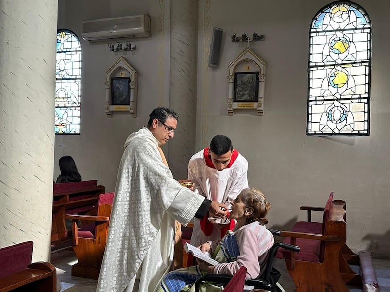 Fr Youssef Asaad distributes Holy Community in Holy Family Parish in Gaza City to a parishioner living with a disability PICTURE: ACN