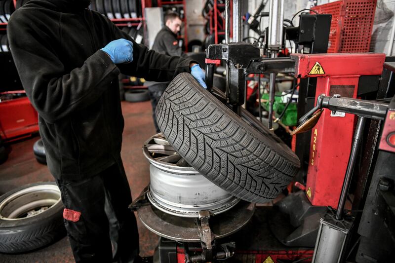 A mechanic works on a car tyre