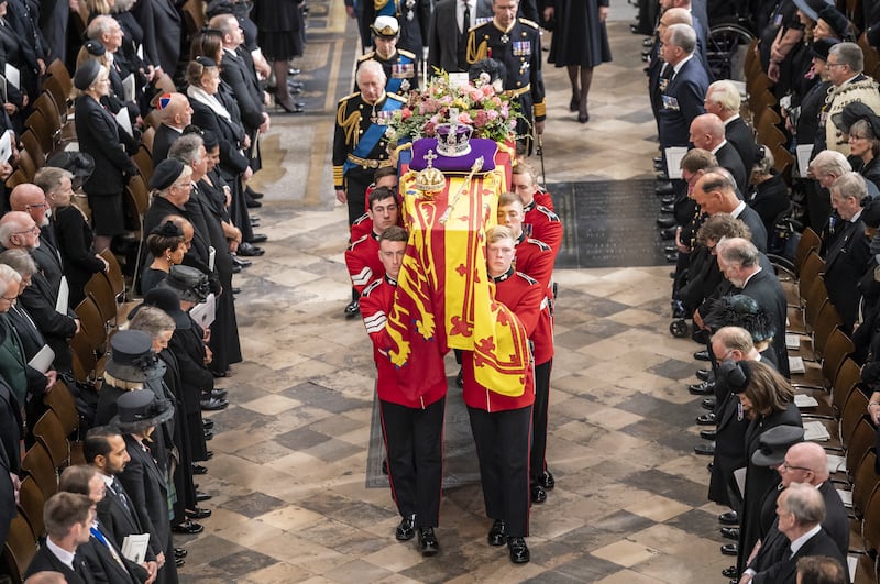 Elizabeth II’s coffin, draped in the Royal Standard with the Imperial State Crown and the Sovereign’s orb and sceptre, is carried out of Westminster Abbey after her state funeral