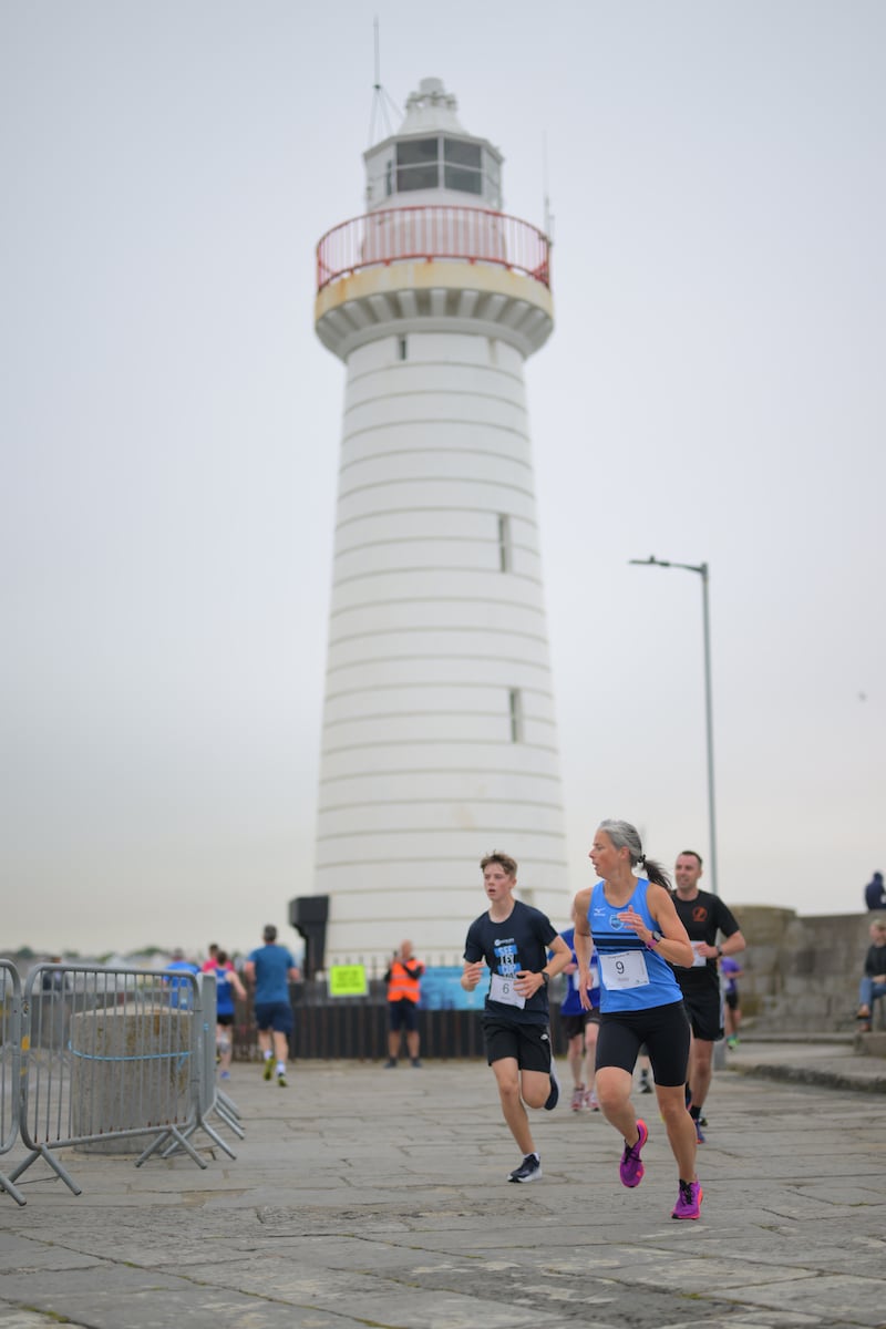 Group of runners in 5k race in front of white lighthouse