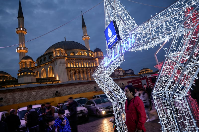 People walk next to luminous shapes in central Istanbul’s Taksim Square, in Istanbul, on Sunday (Emrah Gurel/AP)