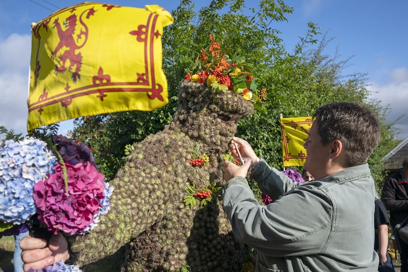 The Burryman receives sips of whisky through a straw during his parade through the town