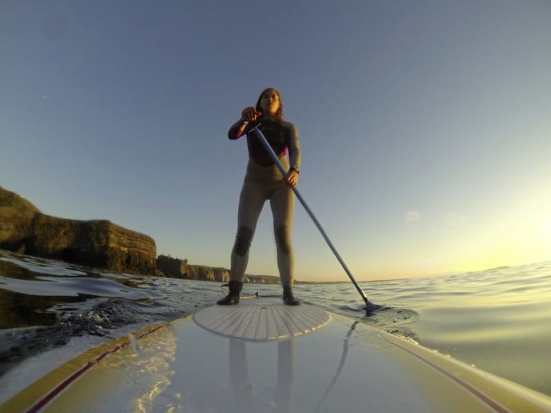 Paddle boarder Jennifer Greenlees on the north Antrim coast, Dunluce in the background 