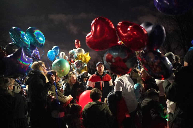 Dalton Hoath (centre) the father of brothers Kyson and Bryson, aged four, and Leyton and Logan, aged three, stands with people prior to a balloon release in Sutton in memory of his sons