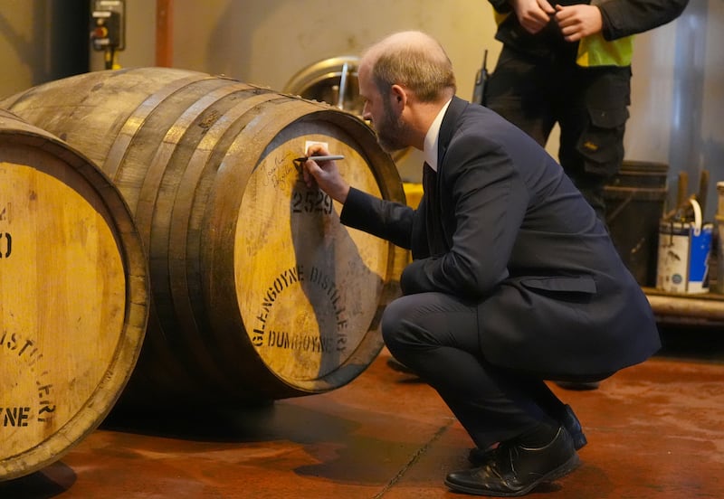 The minister signed a cask after sealing it by hammering in a cork during his distillery visit