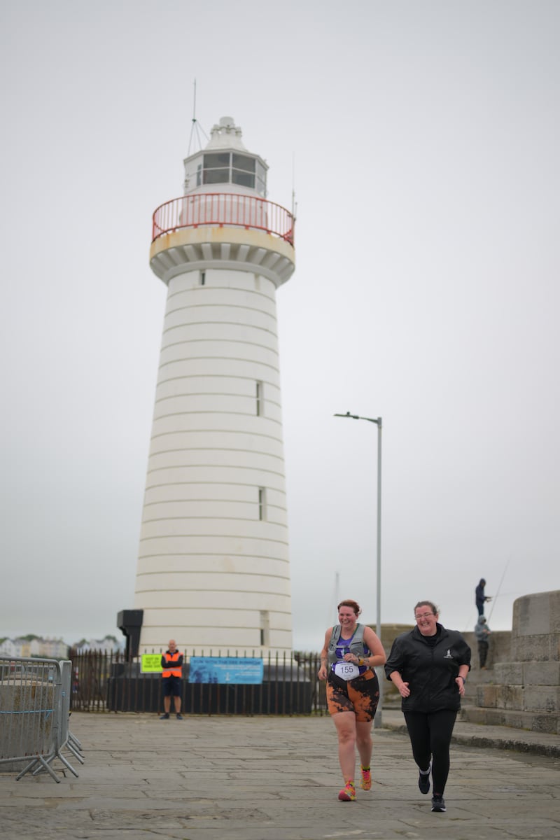 Group of runners in 5k race in front of white lighthouse