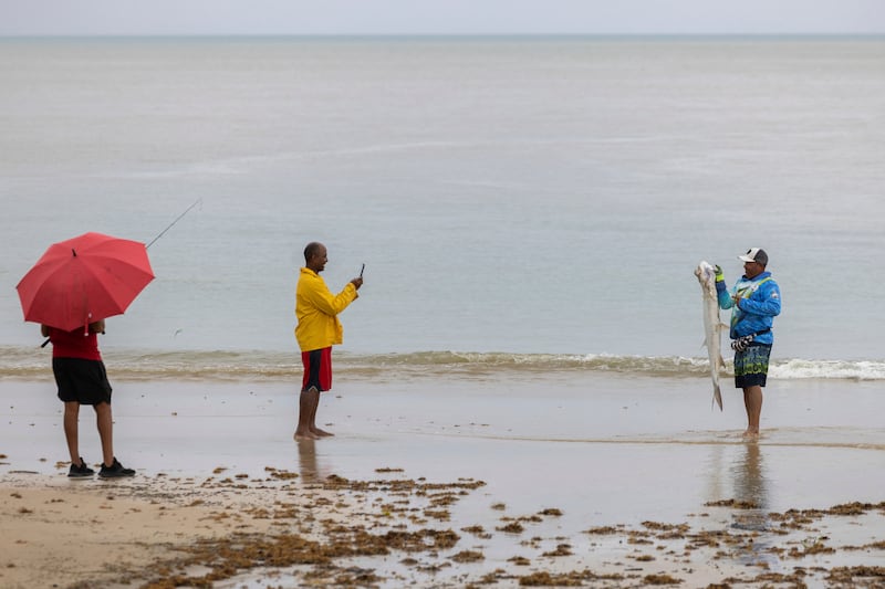 A man poses with a fish after Tropical Storm Ernesto passed through Rio Grande, Puerto Rico