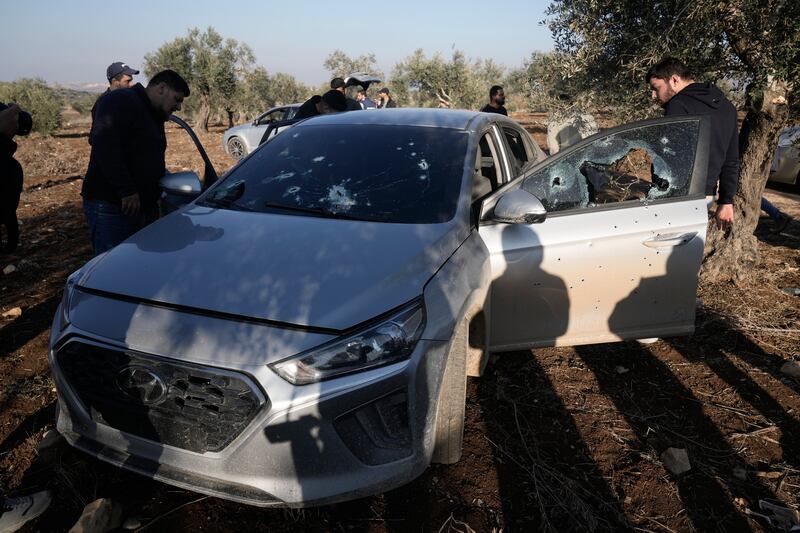 People inspect a car riddled with bullet holes after an Israeli army incursion in the village of Qusra, near Jenin, in the occupied West Bank on Sunday (Majdi Mohammed/AP)