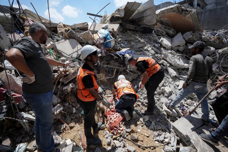 Palestinians rescuers dig around the body of a man in the rubble of a building destroyed in an Israeli airstrike in Nuseirat, Gaza (Abdel Kareem Hana/AP)