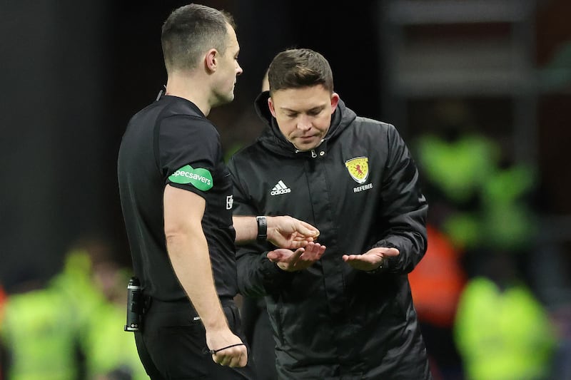 Referee Don Robertson (left) passes an object that was thrown from the crowd towards Celtic’s Arne Engels