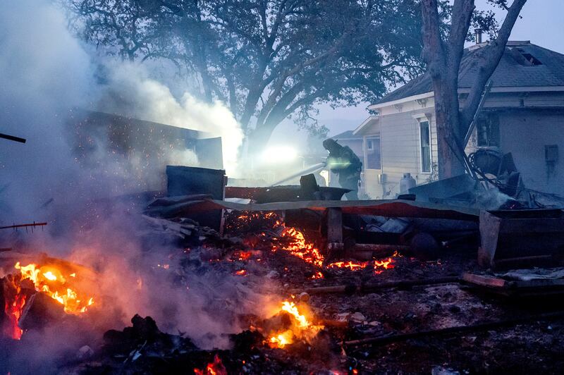 A firefighter sprays water on a burning outbuilding as the Point Fire spreads in Healdsburg, California (Noah Berger/AP)