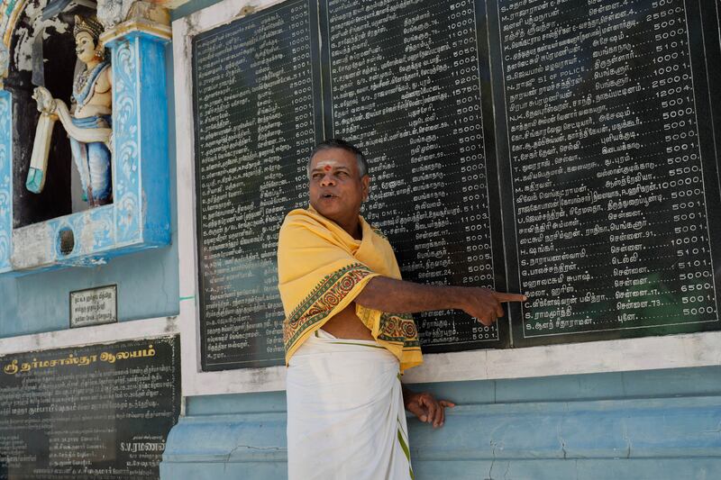 M Natarajan, head priest of Sri Dharmasastha Hindu temple, points out Kamala Harris’s name on a plaque displaying names of donors written in Tamil (Aijaz Rahi/AP)